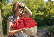 一位女性在高温天气中用手持风扇降温