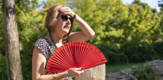 一位女性在高温天气中用手持风扇降温