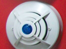 安装在红色墙面上的圆形家用报警器示意，并非被点名的KH158型号