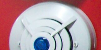 安装在红色墙面上的圆形家用报警器示意，并非被点名的KH158型号