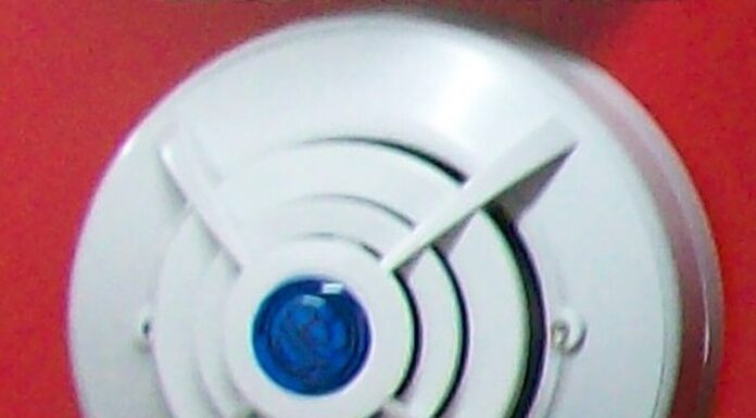 美国消费品安全委员会警告立即停用约376974台KH158插电式四合一天然气与一氧化碳报警器,已知91起未能报警报告 安装在红色墙面上的圆形家用报警器示意,并非被点名的KH158型号